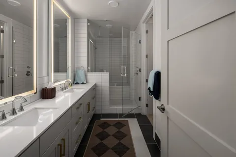 a bathroom with a double vanity sink a mirror and shower