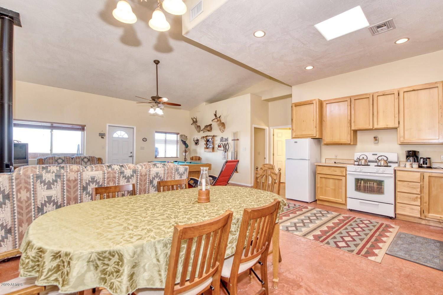 11500 South Duck Tank Road Pearce, AZ 85625 - Photo 6 of 38 a large kitchen with kitchen island a stove a sink a dining table and chairs with wooden floor