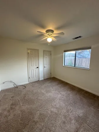 an empty room with a chandelier fan and windows