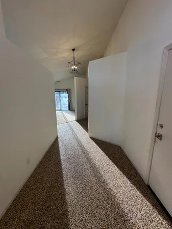 a view of an empty room with a chandelier fan