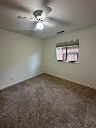 an empty room with a ceiling fan and a window