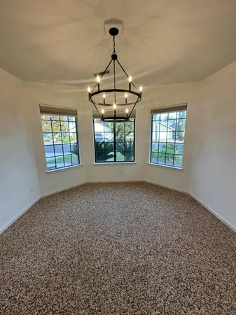 an empty room with windows and chandelier
