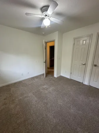an empty room with a chandelier fan and windows
