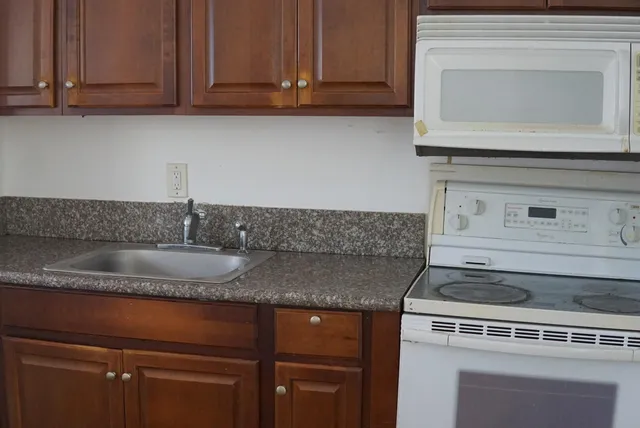 a kitchen with granite countertop a stove sink and cabinets