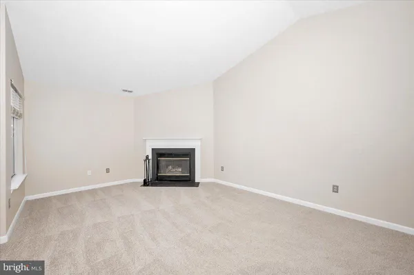a view of an empty room with a fireplace and a window