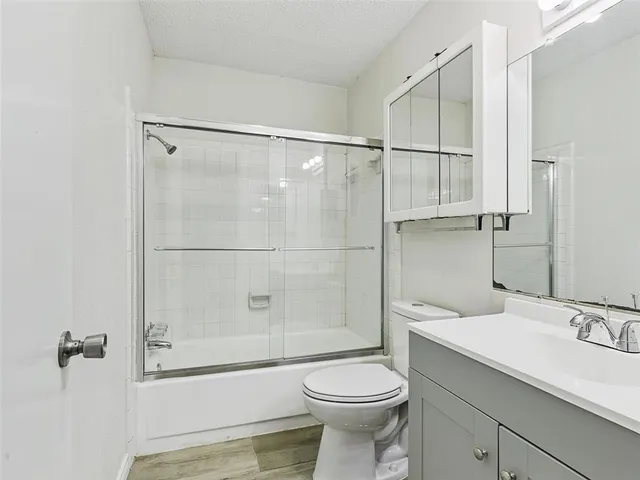 a bathroom with a shower sink vanity mirror and toilet