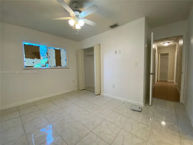 an empty room with kitchen and fan
