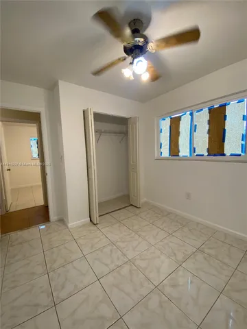 an empty room with windows and fan