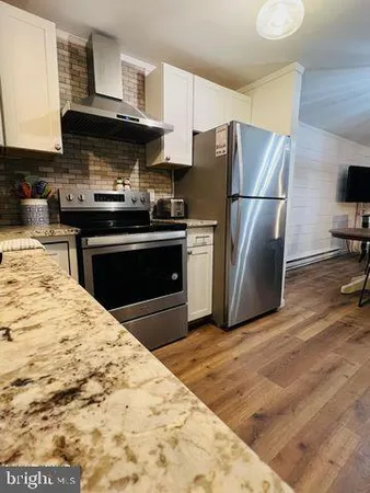 a kitchen with granite countertop a refrigerator and a stove top oven