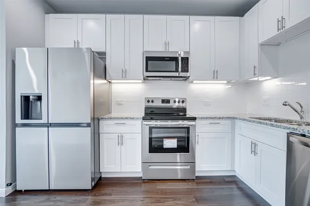 a kitchen with cabinets stainless steel appliances and wooden floor