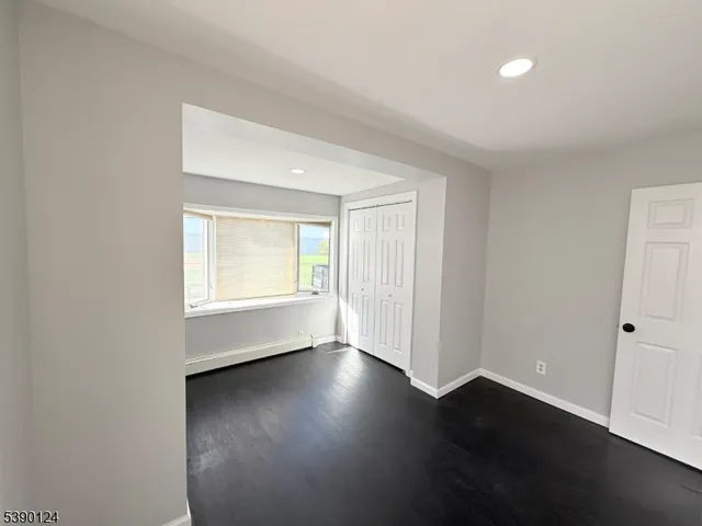 an empty room with wooden floor and windows with curtains