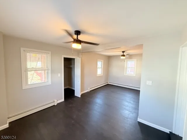 a view of an empty room with a window and wooden floor