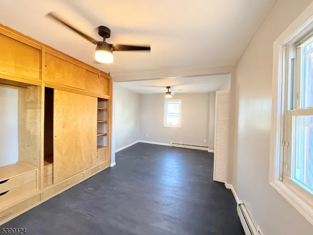an empty room with wooden floor fan and windows