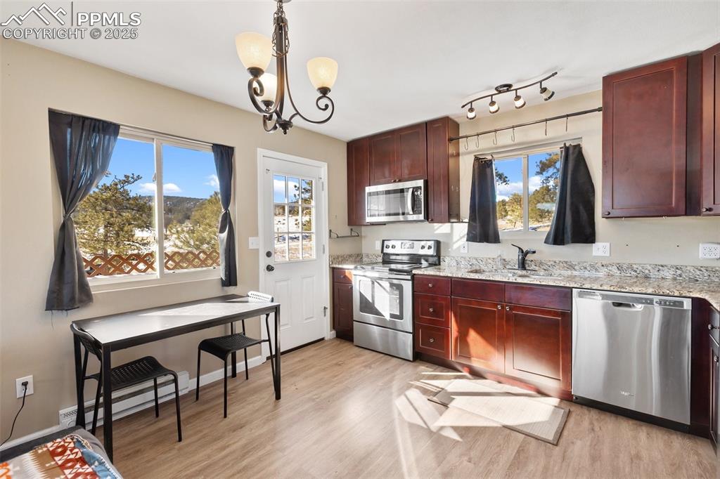 11 Valley Circle Guffey, CO 80820 - Photo 14 of 41 a open kitchen with granite countertop a stove a sink dishwasher a dining table and chairs with wooden floor