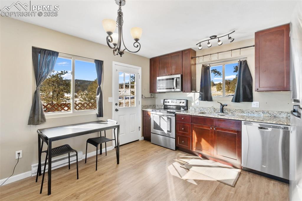 11 Valley Circle Guffey, CO 80820 - Photo 16 of 41 a open kitchen with stainless steel appliances granite countertop a stove a refrigerator a sink dishwasher a dining table and chairs with wooden floor