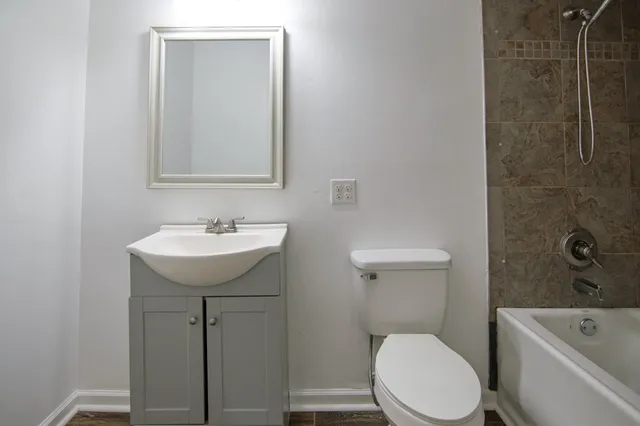 an empty room with wooden floor closet and windows