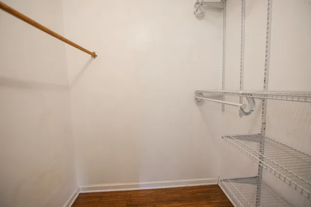 an empty room with wooden floor chandelier fan and windows