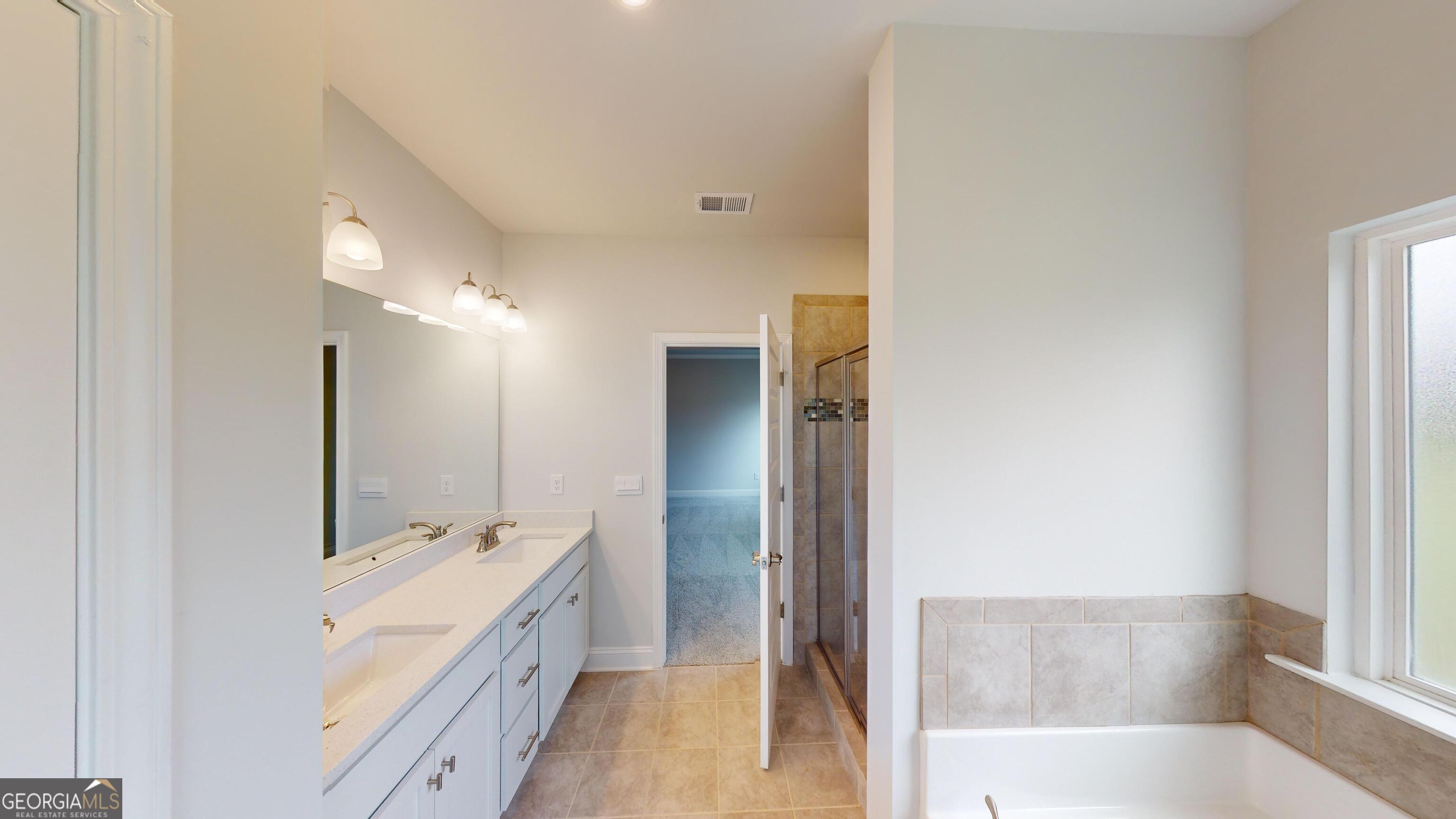1021 Holiday Pass Griffin, GA 30223 - Photo 16 of 22 a spacious bathroom with a double vanity sink a mirror and a bathtub