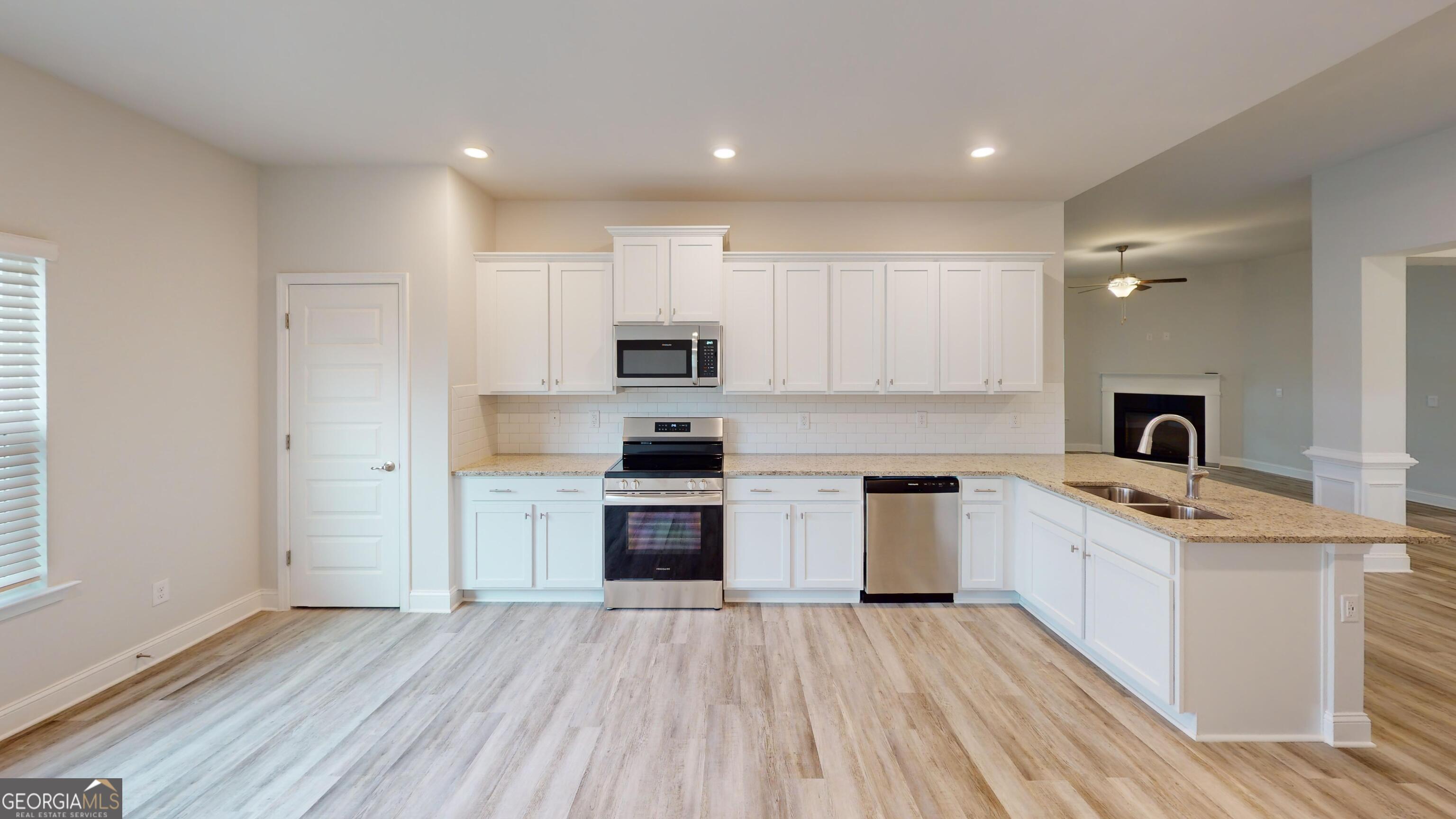 1021 Holiday Pass Griffin, GA 30223 - Photo 7 of 22 a kitchen with stainless steel appliances granite countertop a stove top oven a sink dishwasher and a refrigerator with wooden floor