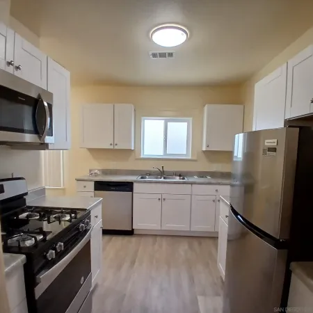 a kitchen with granite countertop a sink stove and refrigerator