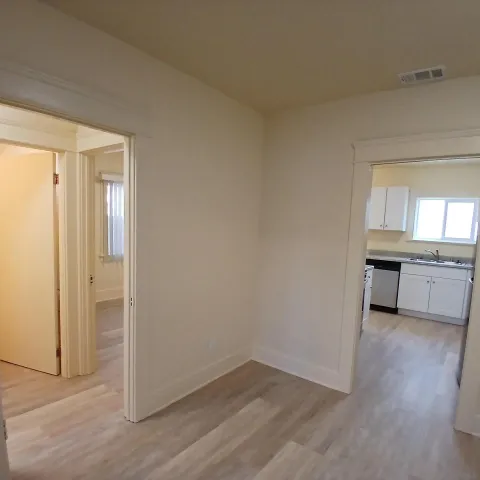 an empty room with wooden floor cabinet and windows