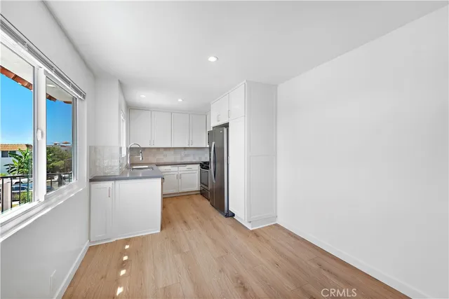 a kitchen with a refrigerator and white cabinets