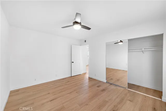 an empty room with wooden floor cabinet and ceiling fan