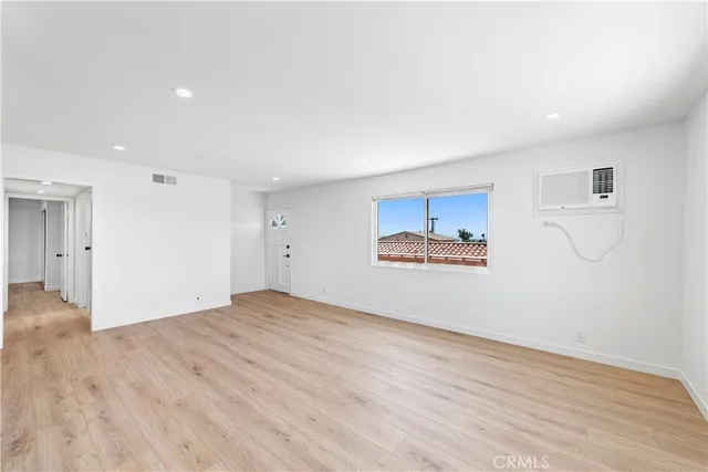 a view of a kitchen and an empty room with wooden floor and a kitchen