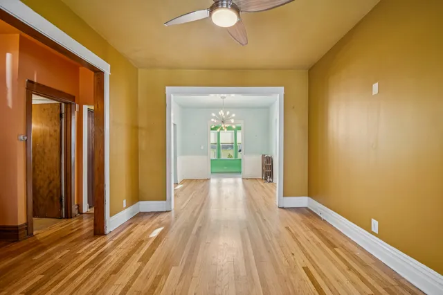 a view of a hallway with wooden floor and a bathroom