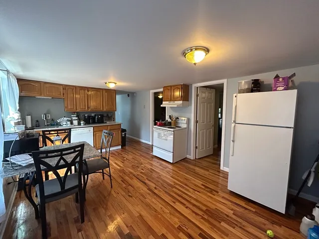 a kitchen with refrigerator and wooden floor