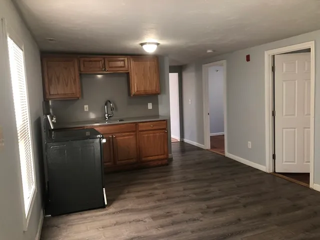 a kitchen with kitchen island granite countertop a sink cabinets and wooden floor