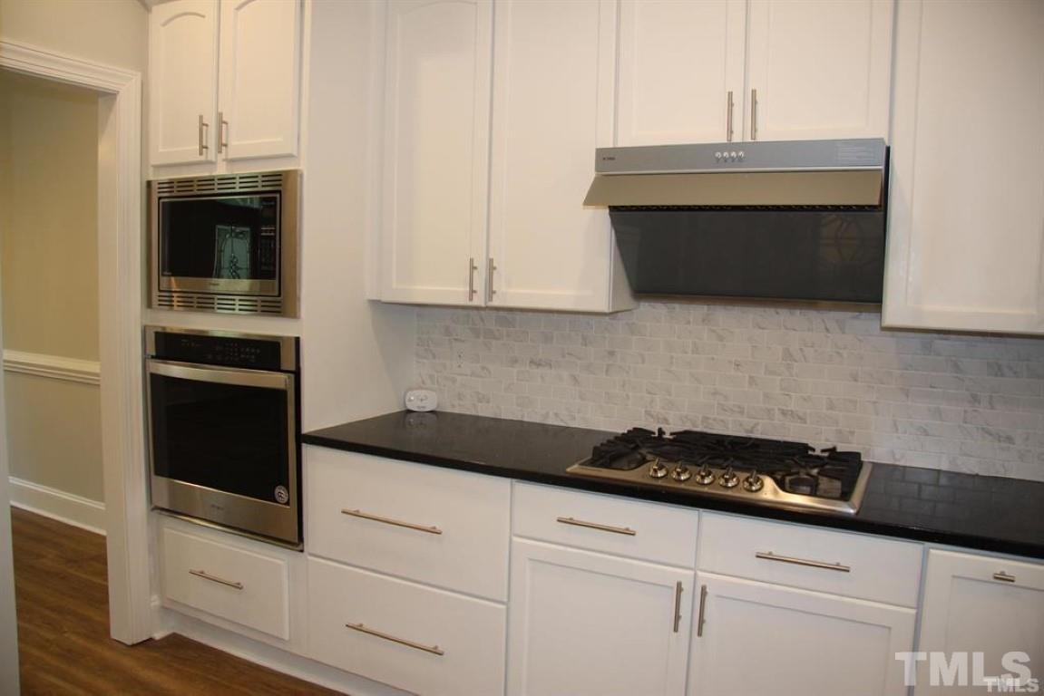 204 Morrow Mountain Drive Cary, NC 27513 - Photo 14 of 40 a kitchen with granite countertop white cabinets and black appliances