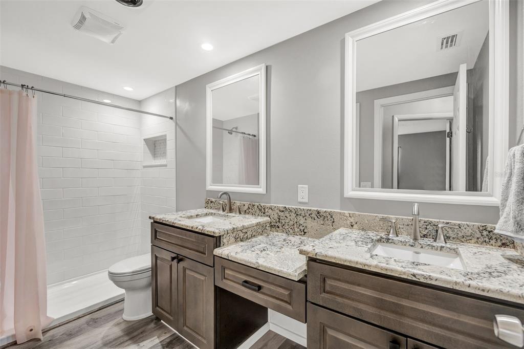 10199 Elgin Boulevard Spring Hill, FL 34608 - Photo 37 of 66 a bathroom with a granite countertop sink a toilet a mirror and shower