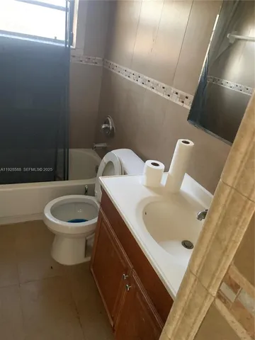 a white toilet sitting next to a bathroom sink and a tub