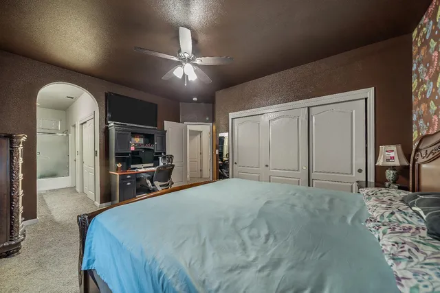 a spacious bedroom with a bed and a flat screen tv