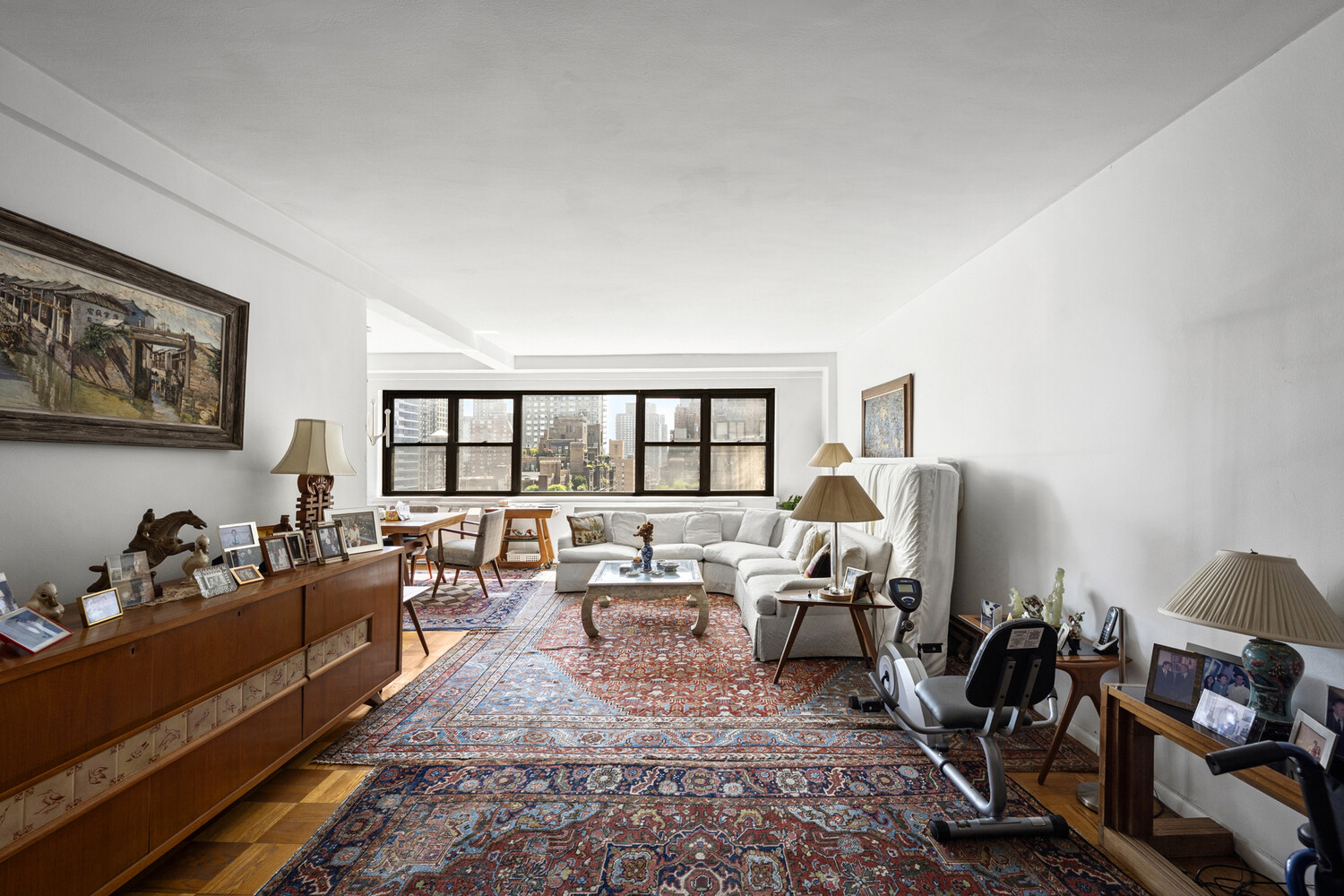 165 East 72nd Street, Unit 12J Manhattan, NY 10021 - Photo 2 of 13 a living room with furniture large window and a table