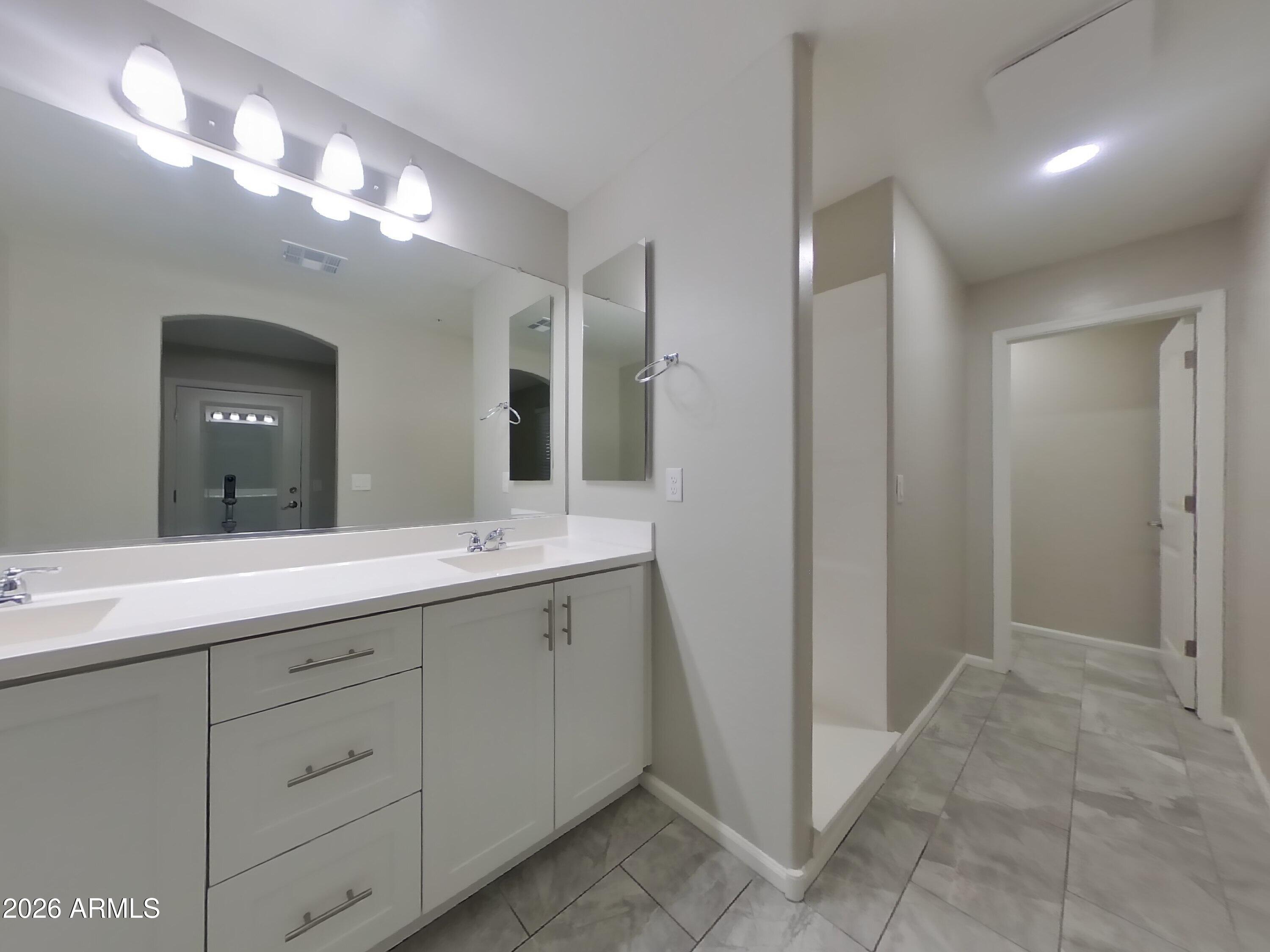 12563 West Gentle Rain Road Peoria, AZ 85383 - Photo 10 of 16 a spacious bathroom with a double vanity sink and a mirror