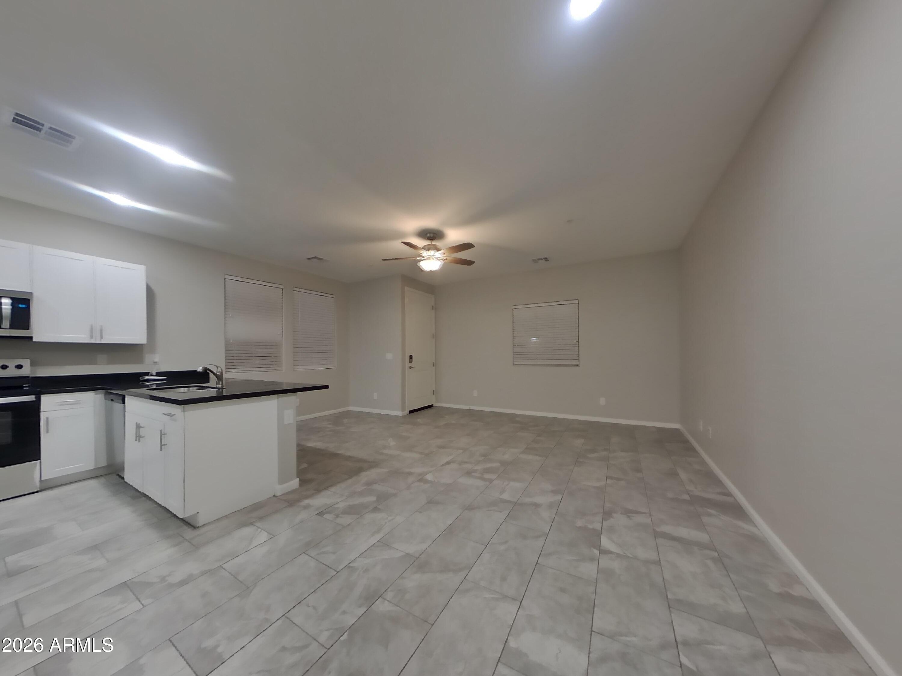 12563 West Gentle Rain Road Peoria, AZ 85383 - Photo 4 of 16 a view of a kitchen with a sink and dishwasher a stove top oven with wooden floor