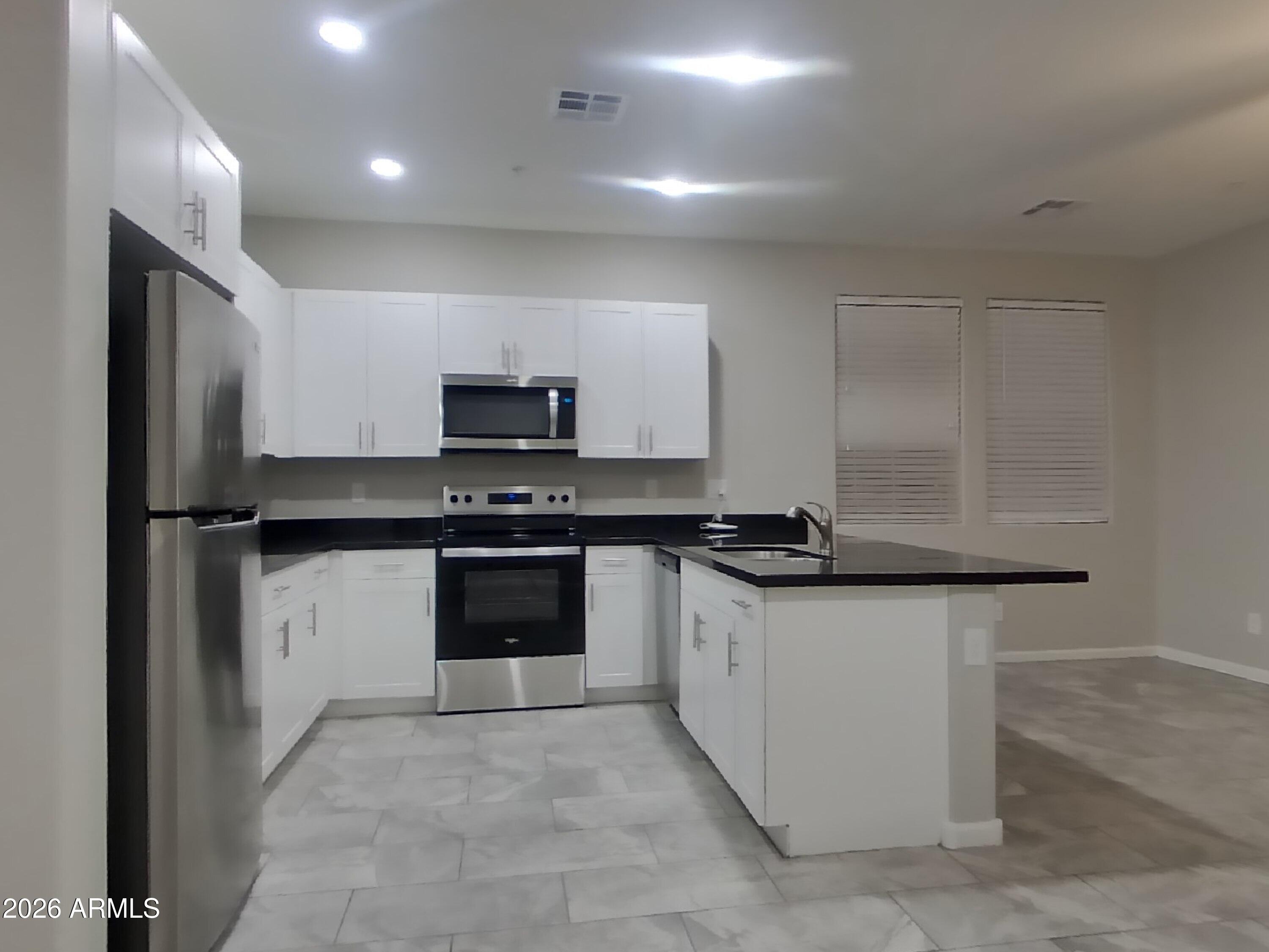 12563 West Gentle Rain Road Peoria, AZ 85383 - Photo 6 of 16 a kitchen with stainless steel appliances a sink stove and refrigerator