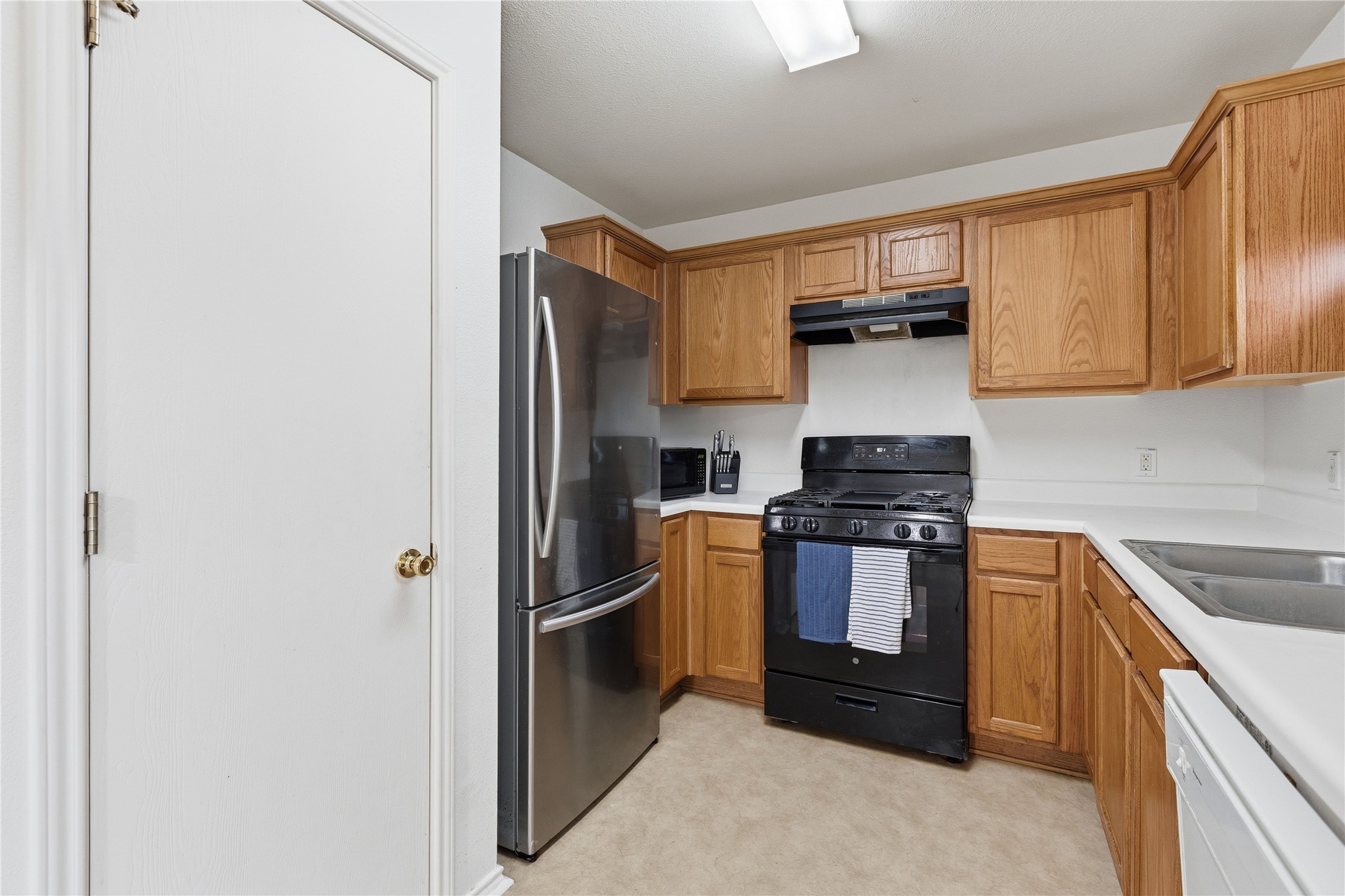 16112 Hamilton Point Circle Manor, TX 78653 - Photo 20 of 27 Kitchen featuring wood cabinetry, white countertops, black range, stainless steel refrigerator, and a stainless steel sink