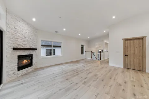 a view of an empty room with wooden floor fireplace and a window