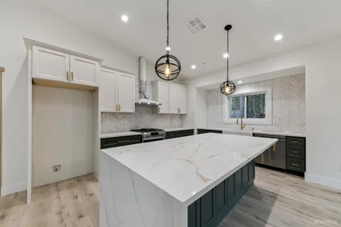a kitchen with a stove a sink a center island and wooden floor