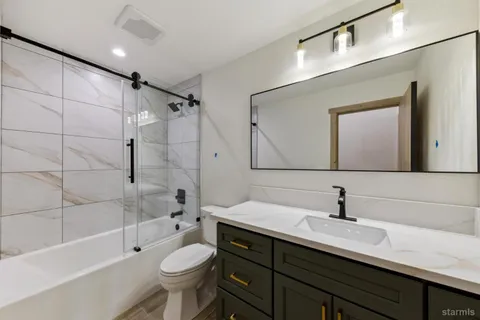 a bathroom with a bathtub shower sink mirror and toilet