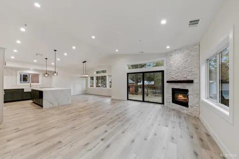 an empty room with kitchen view and fireplace