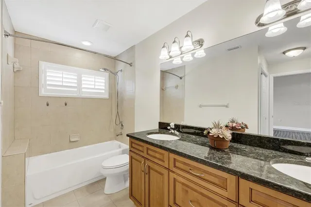 a bathroom with a granite countertop bathtub sink vanity mirror and toilet