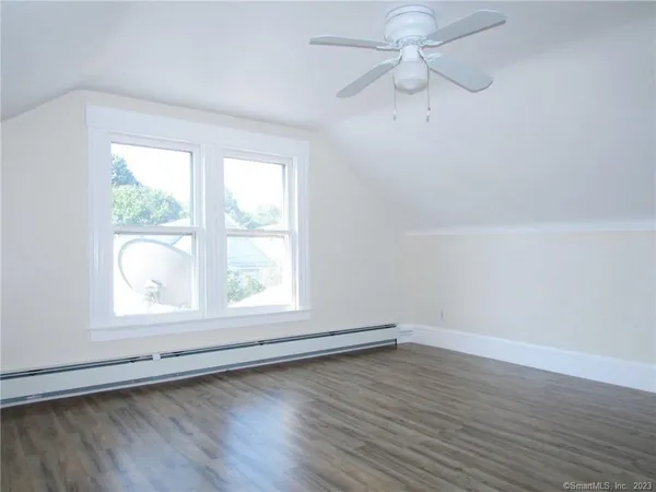an empty room with wooden floor fan and windows