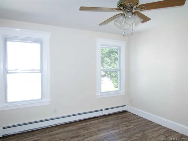 an empty room with wooden floor fan and windows