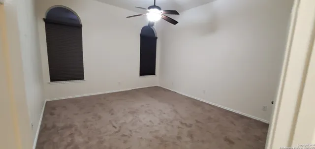 a view of an empty room with chandelier fan and a bathroom