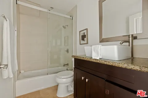 a bathroom with a granite countertop sink toilet and shower