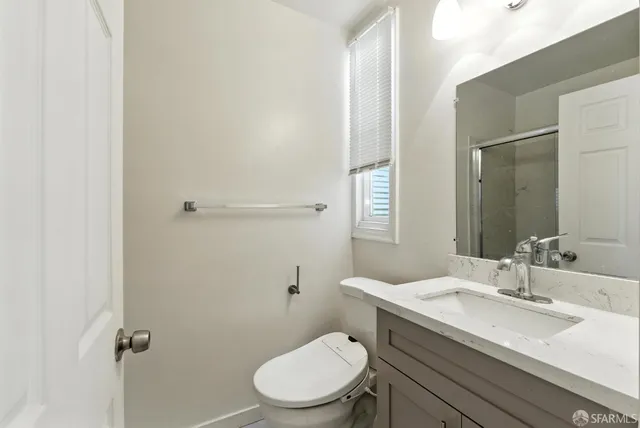 a bathroom with a granite countertop toilet sink and mirror
